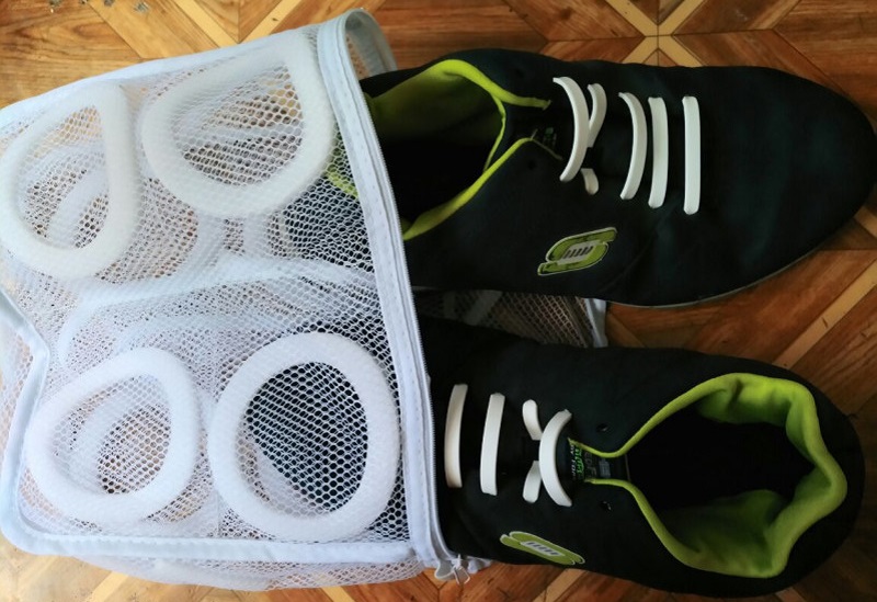 Процесс загрузки кроссовок в специальный мешок для стирки 